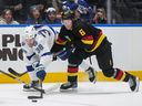 Canucks winger Brock Boeser checks Brandon Hagel of the Lightning during Tuesday clash at Rogeres Arena.