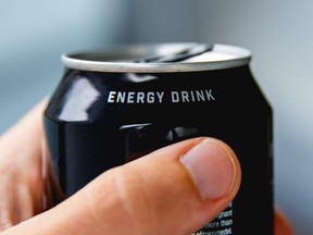 A hand holds a can of an energy drink.