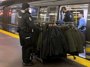 A still from a handout video posted on social media shows Metro Vancouver Transit Police on Monday, Dec. 25, 2023, removing a rolling rack of coats from a SkyTrain car. Police say a 35-year-old man has been arrested and released pending charges after being found with the rack of allegedly stolen coats.