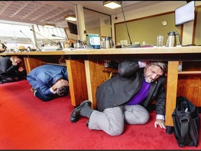 City of Victoria councillors, left to right, Jeremy Caradonna, left, and Chris Coleman do a "Drop, Cover, and Hold On" earthquake drill s part of the Great B.C. ShakeOut in Victoria on Oct. 19, 2023. DARREN STONE, TIMES COLONIST