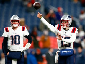 Quarterback Nathan Rourke #13 of the New England Patriots warms up as quarterback quarterback Mac Jones #10 watches prior to the game against the Denver Broncos at Empower Field At Mile High on December 24, 2023 in Denver, Colorado.