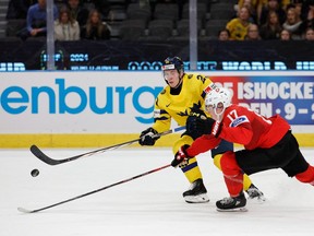 Sweden's Jonathan Lekkerimaki (L) and Switzerland's Miles Muller vie for the puck during the quarter-final match between Sweden and Switzerland of the IIHF World Junior Championship in Gothenburg, Sweden on January 2, 2024.