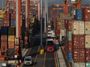 Cargo containers are moved by trucks at the Port of Vancouver Centerm container terminal as others are stacked under gantry cranes, in Vancouver, on Friday, Oct. 14, 2022.