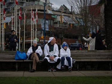 A family in robes waits to participate in the Polar Bear Swim on New Year's Day at English Bay Beach in Vancouver, B.C., Monday, Jan. 1, 2024.