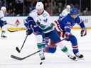 Rangers winger K'Andre Miller fights for control of the puck against Elias Pettersson of the Canucks on Monday at Madison Square Garden.