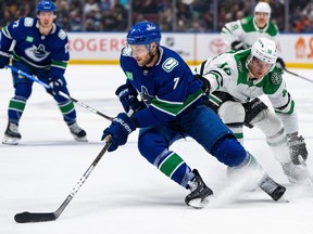 Dallas Stars' Ty Dellandrea (10) grabs Vancouver Canucks' Carson Soucy (7) as he skates with the puck during the first period in Vancouver, on Saturday, Nov. 4, 2023.