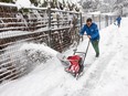 Aayush Diwan of Snowpros Snow Removal uses a blower to clear the sidewalk on Prairie Avenue in Port Coquitlam on Jan. 17, 2024.