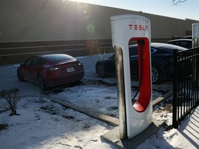Tesla vehicles charge in a snow and salt covered parking lot on January 17, 2024 in Chicago, Illinois.