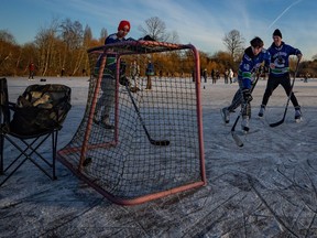 People dressed in Vancouver Canucks jerseys play hockey on frozen Trout Lake amid a cold snap in Vancouver on Sunday, Jan. 14, 2024.