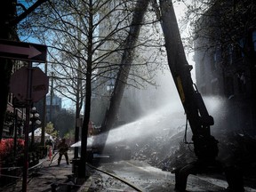 A coroner's inquest into the deadly Winters Hotel fire in Vancouver has seen video footage of the blaze from inside the rooming facility, showing heavy smoke billowing from a unit, then flames a few minutes later. A firefighter sprays water on debris during demolition of the Winters Hotel in Vancouver, B.C., Friday, April 22, 2022.