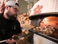 Erik Mandracchia takes a pizza from the wood burning oven at Montreal's restaurant Fiorellino in 2018.