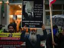Un homme tient une pancarte avec une photo de Hardeep Singh Nijjar lors d'une manifestation devant le consulat indien à Vancouver le lundi 25 septembre 2023. Le porte-parole d'un groupe prônant l'indépendance sikh a déclaré qu'une maison de la région métropolitaine de Vancouver touchée par des coups de feu jeudi appartenait à un membre du mouvement.