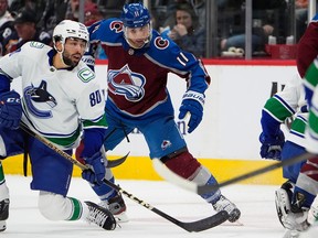 Vancouver Canucks left wing Arshdeep Bains, left, jostles for position with Colorado Avalanche centre Andrew Cogliano in the first period on Tuesday in Denver