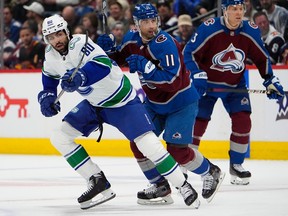 Vancouver Canucks left wing Arshdeep Bains, left, pursues the puck with Colorado Avalanche centre Andrew Cogliano in the first period on Tuesday in Denver.