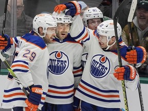 Edmonton Oilers' Evan Bouchard, second rom right, celebrates an overtime goal with teammates Leon Draisaitl (10) and Derek Ryan (11) during the third period an NHL hockey game against the Dallas Stars in Dallas, Saturday, Feb. 17, 2024.