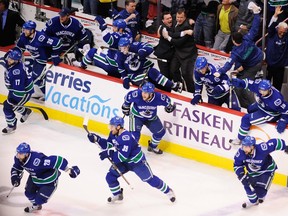 Vancouver Canucks head coach Alain Vigneault (right) and assistant coach Newell Brown (left) embrace each other as players leap off the bench after Kevin Bieksa (not shown) scores against the San Jose Sharks during the second overtime to win game five and the Western Conference Championship in the 2011 NHL Stanley Cup Playoffs at Rogers Arena in Vancouver on May 24, 2011.