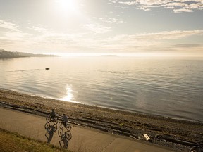 A couple cycling along a seawall in Victoria.
