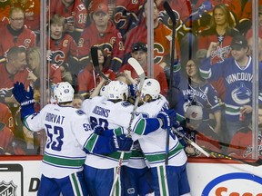 The Canucks celebrate a goal in front of a sea of Calgary Flames fans.