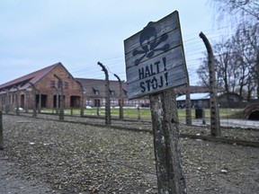 Warning signs hang by the barbed wire fence at the former Nazi Auschwitz Concentration Camp in Oswiecim, Poland in 2023.