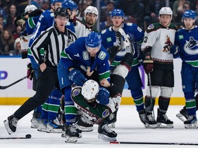 Vancouver Canucks' Carson Soucy grapples with Arizona Coyotes' Michael Carcone during the second period of an NHL game in Vancouver on Thursday, Jan. 18, 2024.