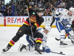 Canucks' Carson Soucy battles Toronto's William Nylander for the puck in a Jan. 20, 2024 game at Rogers Arena.