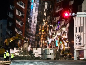 Emergency personnel stand in front of a partially collapsed building leaning over a street in Hualien on April 3 after a major earthquake hit Taiwan's east. At least nine people were killed and more than 1,000 injured by the quake that damaged dozens of buildings and prompted tsunami warnings that extended to Japan and the Philippines before being lifted.