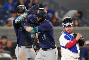 Seattle Mariners' Mitch Haniger celebrates his two-run home run with Julio Rodriguez, left, as Blue Jays catcher Alejandro Kirk looks on during the eighth in Toronto on Tuesday, April 9, 2024.