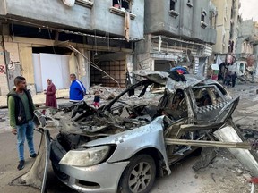 Onlookers check the car in which three sons of Hamas leader Ismail Haniyeh were reportedly killed in an Israeli air strike in al-Shati camp, west of Gaza City on April 10, 2024