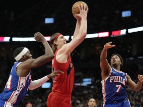 Toronto Raptors forward Kelly Olynyk (41) drives to the hoop as Philadelphia 76ers forward Paul Reed (44) and Philadelphia 76ers guard Kyle Lowry (7) defend during first half NBA basketball action in Toronto, Sunday, March 31, 2024.