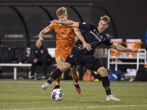 Forge FC midfielder Noah Jensen (left) fights for a ball with Cavalry FC defender Daan Klomp (4) during the Canadian Premier League final soccer action in Hamilton on Saturday, Oct. 28, 2023. While still a work in progress, the Canadian Premier League kicks off its sixth season Saturday with a feeling of stability.