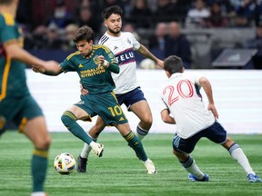 Los Angeles Galaxy's Riqui Puig (10) evades Vancouver Whitecaps' Ryan Raposo, back centre, and Andres Cubas (20) during the first half of an MLS soccer match, in Vancouver, on Saturday, April 13, 2024.