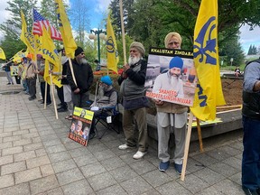 The accused appeared by video in front of a packed courtroom with another 50 in an overflow room and another hundred waving flags and carrying signs outside Surrey court.