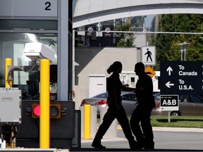 Canadian border guards are silhouetted as they replace each other at an inspection booth at the Douglas border crossing on the Canada-USA border in Surrey, B.C., on August 20, 2009. More than 9,000 members of the Public Service Alliance of Canada working for the Canada Border Services Agency have voted in favour of taking strike action.