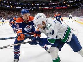 Vancouver Canucks' Elias Pettersson (40) is checked by Edmonton Oilers' Vincent Desharnais (73) during first period NHL action in Edmonton on April 13, 2024.