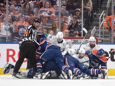 Vancouver Canucks and Edmonton Oilers fall into the net on a loose puck during first period second-round NHL playoff action in Edmonton on Sunday May 12, 2024.THE CANADIAN PRESS/Jason Franson