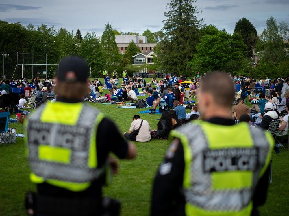 Vancouver Police officers watch over a crowd gathered to watch Vancouver Canucks play the Edmonton Oilers at a 