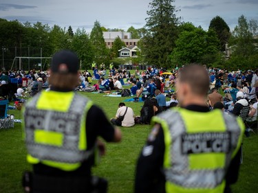 Vancouver Police officers watch over a crowd gathered to watch Vancouver Canucks play the Edmonton Oilers at a "Playoffs in the Park" viewing party for the third game in the second round of the Stanley Cup playoffs, in Vancouver, B.C., Sunday, May. 12, 2024.