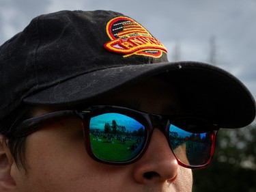 A crowd, gathered to watch Vancouver Canucks play the Edmonton Oilers at a "Playoffs in the Park" viewing party, is reflected in a fan's sunglasses in Vancouver, B.C., Sunday, May. 12, 2024.