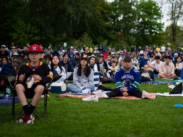 People watch the Vancouver Canucks play the Edmonton Oilers at a "Playoffs in the Park" viewing party for the third game in the second round of the Stanley Cup playoffs, in Vancouver, B.C., Sunday, May. 12, 2024.