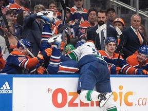 Vancouver Canucks' Nikita Zadorov (91) checks Edmonton Oilers' Evander Kane into the bench during the second period
