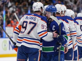 Quinn Hughes, do Vancouver Canucks, dianteiro direito, e Connor McDavid, do Edmonton Oilers, conversam enquanto apertam as mãos depois que Edmonton derrotou Vancouver durante o jogo 7 da série de playoffs da segunda rodada da Stanley Cup de hóquei da NHL, em Vancouver, na segunda-feira, 20 de maio de 2024.