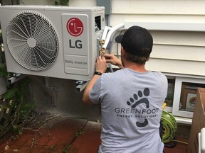 A Greenfoot Energy Solutions installation technician puts the final touches on a new heat pump system for a residential building.