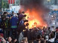 Vancouver Canucks fans watch a car burn during a riot following game 7 of the NHL Stanley Cup final in downtown Vancouver, on June 15, 2011.