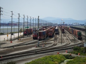 Trains are seen as cargo containers sit idle on rail tracks in Delta, B.C., on Friday, July 7, 2023. The U.S. Department of Justice in Washington State says two men are facing human smuggling charges for their alleged role in a scheme to get people across the Canada-U.S. border in B.C. on freight trains.