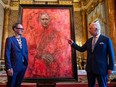 Artist Jonathan Yeo and King Charles III stand in front of the portrait of the King as it is unveiled in the blue drawing room at Buckingham Palace on May 14, 2024 in London, England.