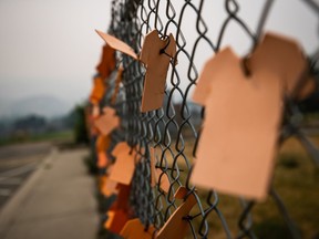 Cutouts of orange T-shirts are hung on a fence outside the former Kamloops Indian Residential School, in Kamloops, B.C., Thursday, July 15, 2021.