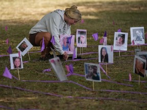 Taylor Snider adjusts a photograph of an overdose victim as members of Moms Stop the Harm mark International Overdose Awareness Day in Vancouver, on Thursday, Aug. 31, 2023. A report from British Columbia's coroners service says 126 children and youth younger than 19 died from toxic drugs between 2019 and 2023.