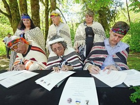 In the front row, left to right, Chief Pahalicktun Richard Thomas (Lyackson First Nation), Chief Sulsulxumaat Cindy Daniels (Cowichan Tribes), and Premier David Eby sign a land-transfer deal at Skutz Falls. In the back row, left to right, are Laxele'wuts' aat Shana Thomas (Lyackson First Nation), Murray Rankin, minister of Indigenous Relations and Reconciliation, and Sunaxwumaat Dana Thorne (Cowichan Tribes).