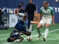 Vancouver Whitecaps' Ali Ahmed (left) falls in front of Austin FC's Alexander Ring (8) as they vie for the ball during the first half of an MLS soccer match in Vancouver, on Saturday, May 4, 2024.