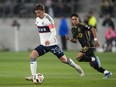 Vancouver Whitecaps midfielder Ryan Gauld (25) controls the ball ahead of Los Angeles FC defender Erik Dueñas (18) during the second half of an MLS soccer match in Los Angeles on May 11, 2024.